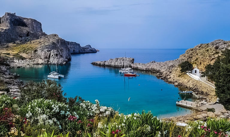 Rhodes Greece ships on water surrounded by rocks and flowers