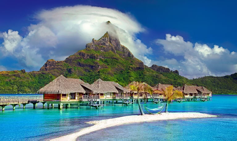 Bora Bora houses on water with mountain peak in distance