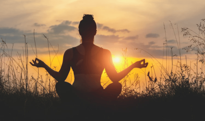 femme de dos en position de méditation en exterieur
