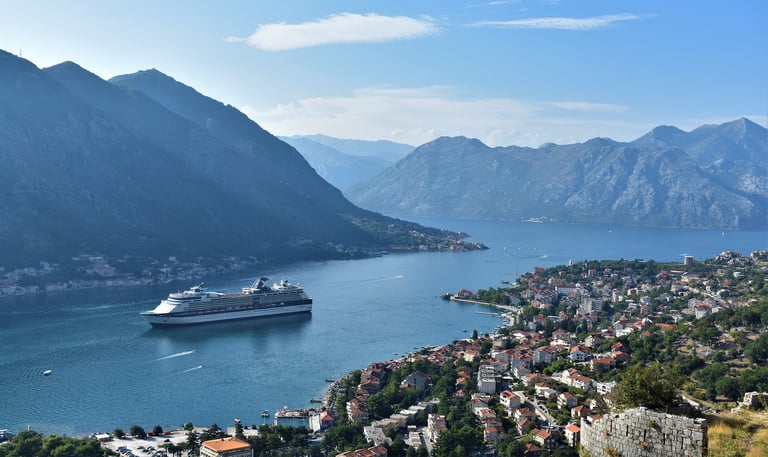 Cruise ship sailing to Port of Kotor Montenegro with houses and mountains in distance