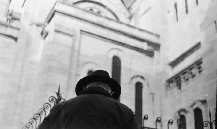 homme à chapeau en contre plongée devant le sacré coeur de Paris