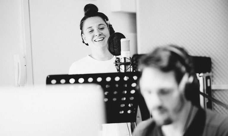 Female vocalist recording in studio booth during vocal session