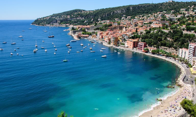 Coast of Villefranche sur mer coast with blue water, beach, sailboats and housing