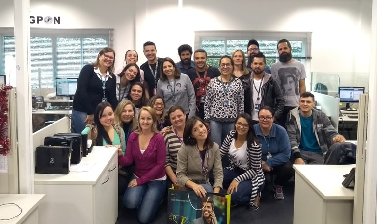 uma equipe de trabalho, um grupo de pessoas em pé ao redor de uma mesa posando para uma foto