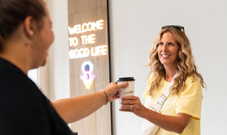 a woman is handing a cup of coffee to a customer