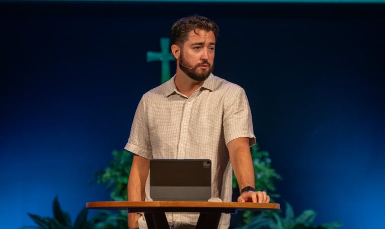 Pastor standing at pulpit relaxed.