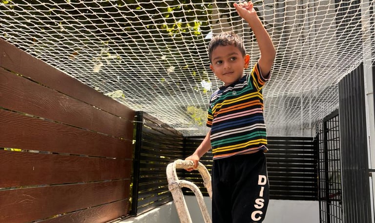 A spacious open terrace surrounded by sturdy safety nets with children playing safely inside.