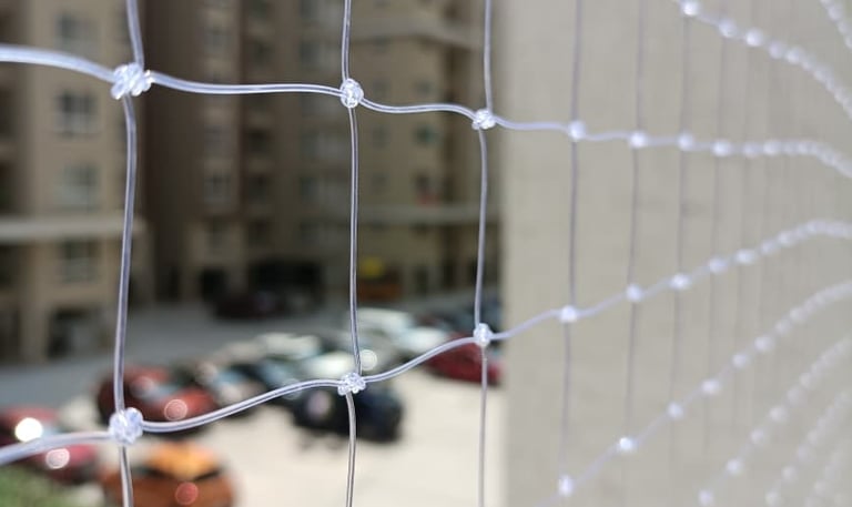 Close-up of a tightly woven pigeon safety net installed on a balcony in Electronic City.