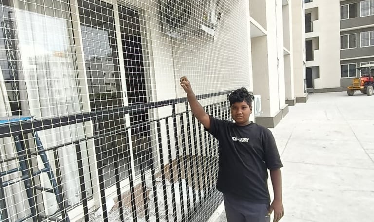 Workers installing child safety nets on a high-rise apartment in Electronic City under clear skies.