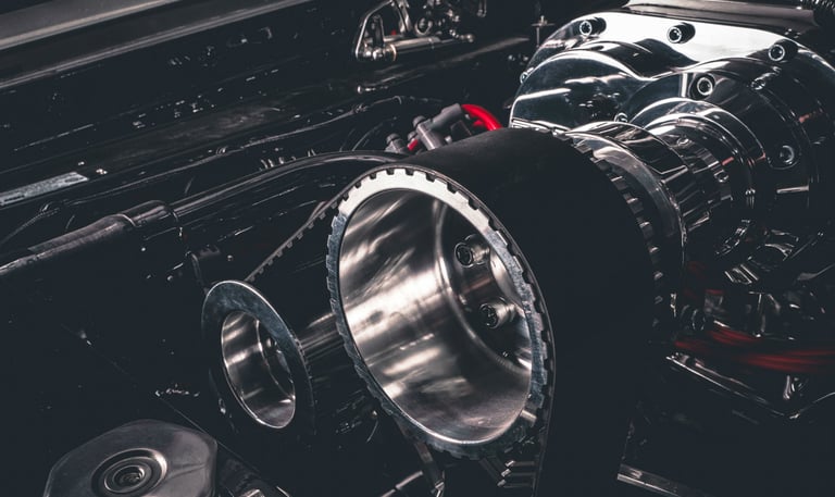 Close-up of a high-performance chrome supercharger with a drive belt on a custom car engine.