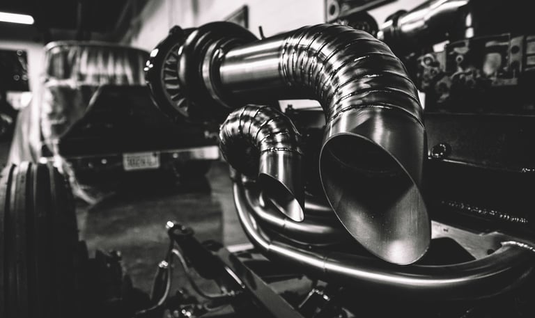 Custom stainless steel turbocharger exhaust piping with precise welds on a diesel truck engine.