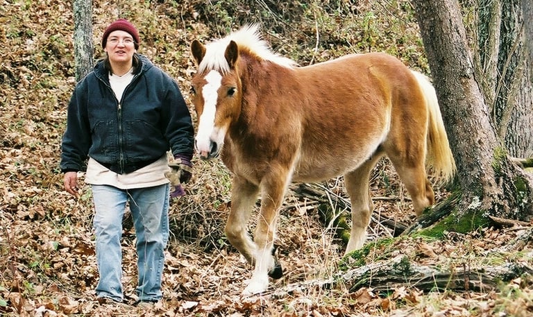 Leah Kyaio leading a pony in the woods without a lead