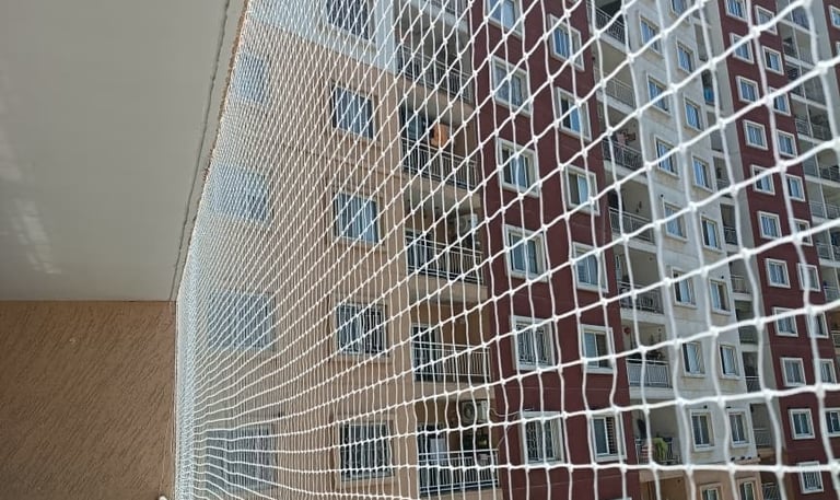 Close-up of a newly installed pigeon net wrapping an apartment balcony in Arekere.