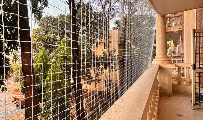 Wide shot of a spacious balcony covered with durable pigeon netting amid urban Mumbai surroundings.