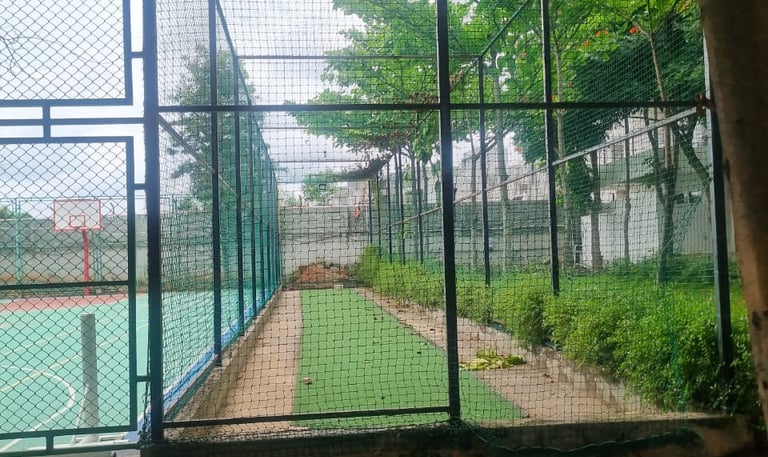 Close-up of tightly fastened basketball court nets with players warming up in the background.