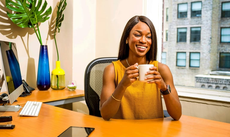 Woman at desk smiling and holding a mug