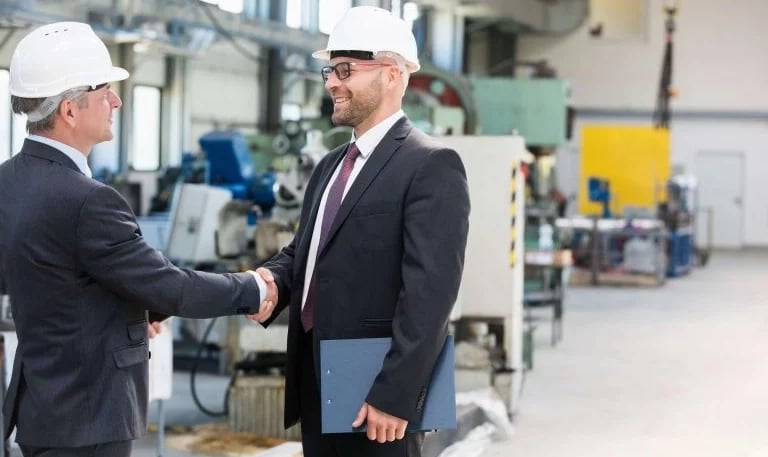 two men shaking hands in a factory