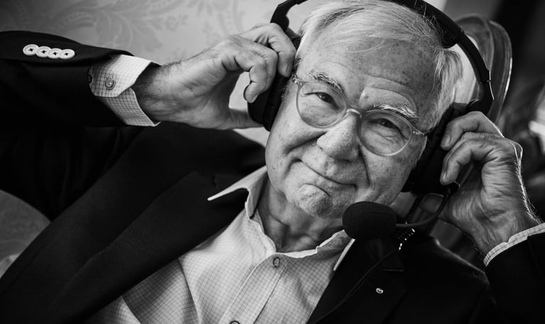 ein Mann im Anzug und mit Brille trägt ein Headset