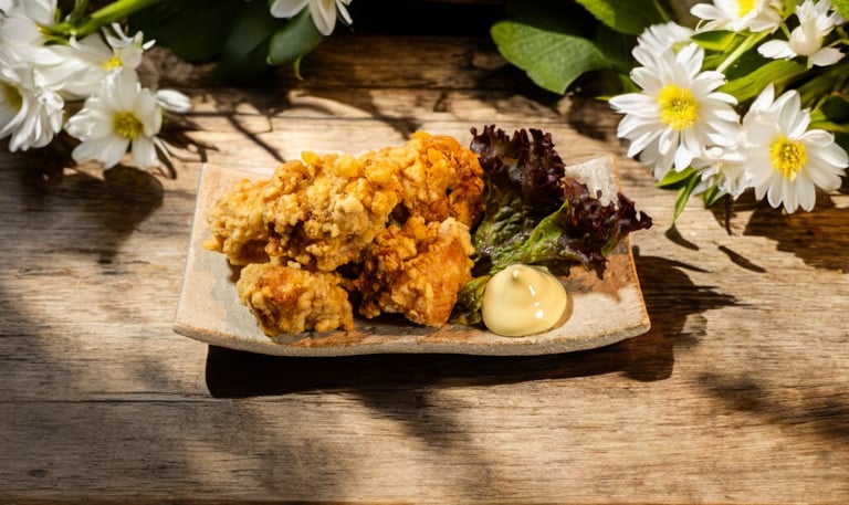 Crispy Japanese chicken karaage served with creamy mayo and lettuce on a rustic wooden table with white daisies.