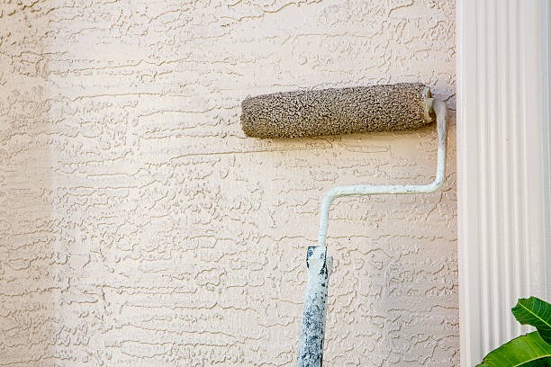 a paint roller painting a stucco wall with a roller roller
