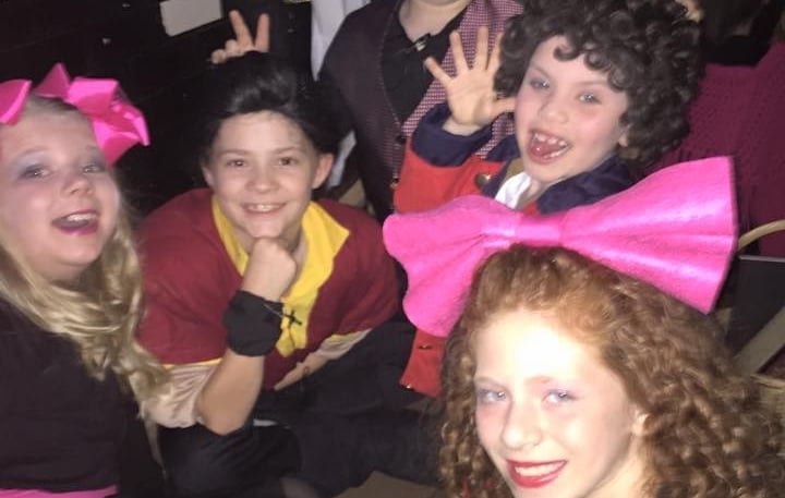 a group of kid actors posing for a picture backstage connecting as friends.