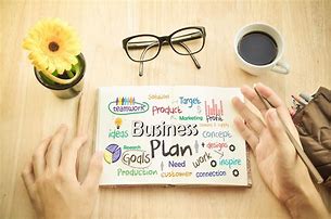 the view of a desk with a yellow flower, glasses, a cup of coffee and a business plan