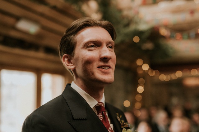 a man in a suit and tie with a flower in his hand