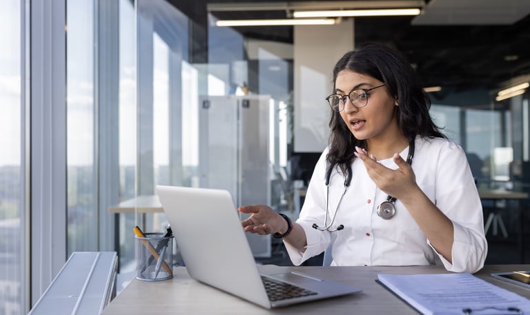 Doctora en consulta de telemedicina interactuando con un paciente a través de una videollamada.