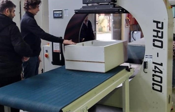 a man standing in front of a machine that is cutting into a piece of paper