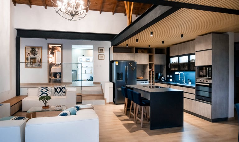 Cocina moderna de concepto abierto, isla central negra, iluminación empotrada y acabados en madera