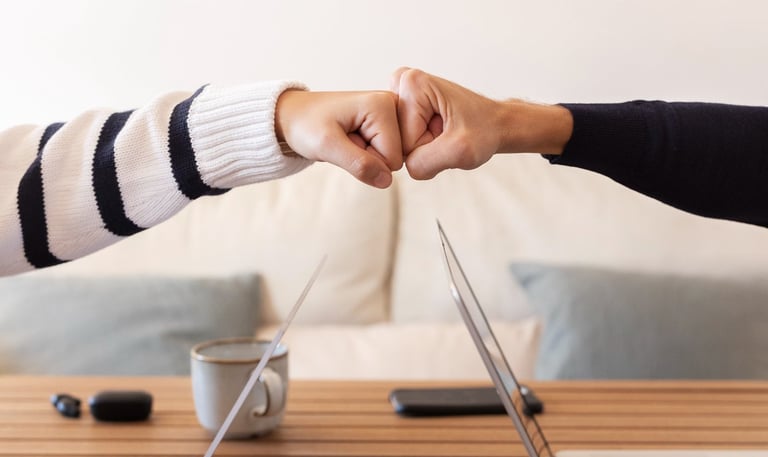 two people shaking hands over a laptop