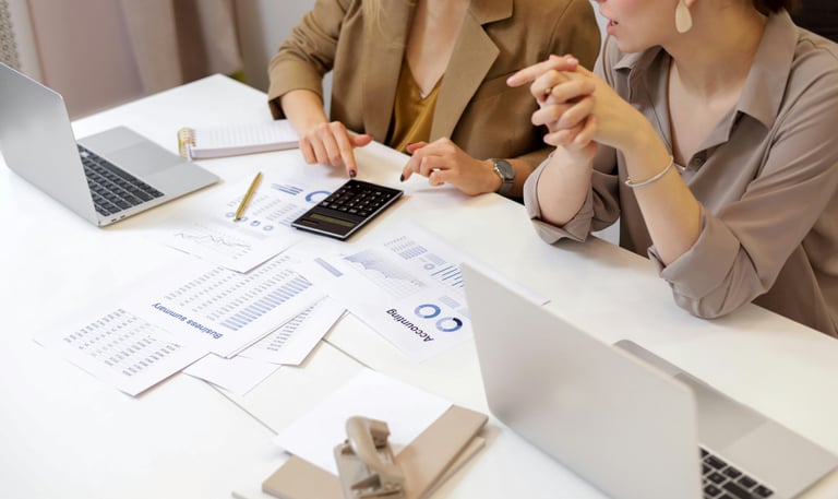 two women sitting at a table with papers and papers