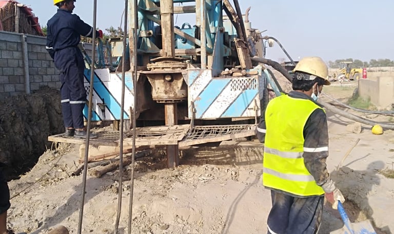 a man in a yeellow vest drilling a well