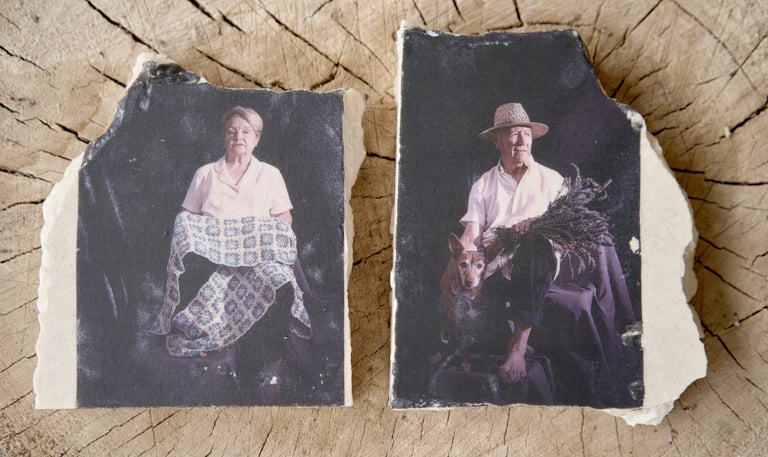 Antique style portraits of an elderly couple printed on broken ceramic slabs over a wood stump.
