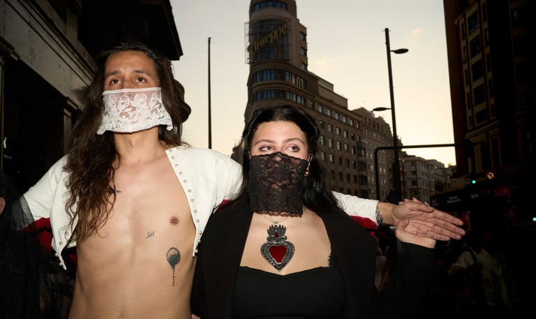 Two people in gothic fashion with lace masks pose near the Capitol building in Madrid.
