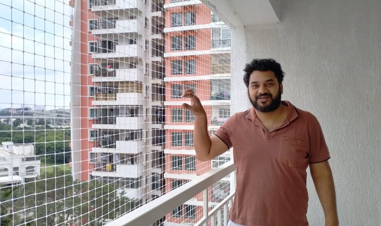 Close-up of a freshly installed pigeon net on a Mumbai balcony with cityscape in the background.