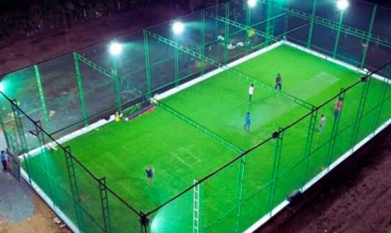 A freshly installed sturdy sports net enclosing a rooftop cricket pitch under a clear blue sky.