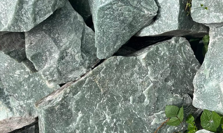 Rochas brutas de quartzo aventurina verde e minerais naturais em uma formação cristalina irregular.
