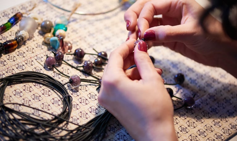 mujer creando joyeria a mano con piedras preciosas