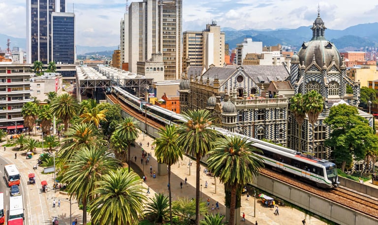 Elevated Metro train passing the Palacio de la Cultura and palm trees in downtown Medellin, Colombia.