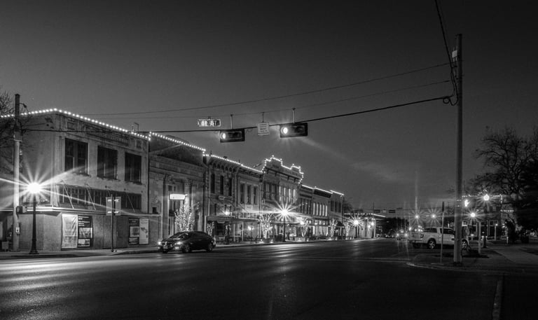 Night photo of Austin Ave in Georgetown, Texas, with it's historic buildings illuminated by streetlights
