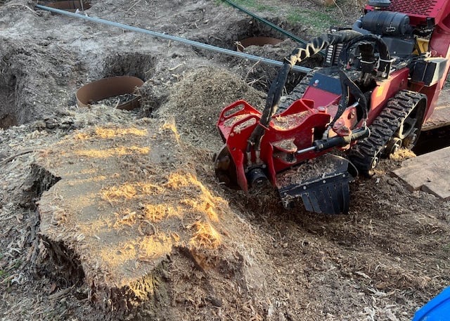 a man is using a stump grinder to cut down a tree stump