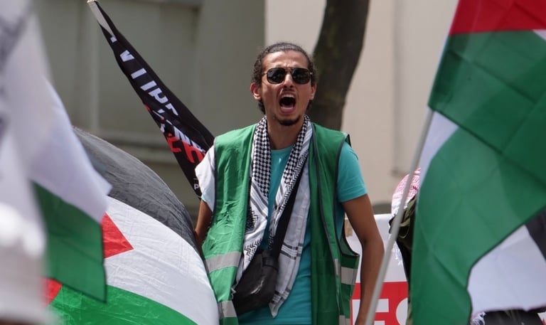 a man in a green vest and sunglasses with a flag