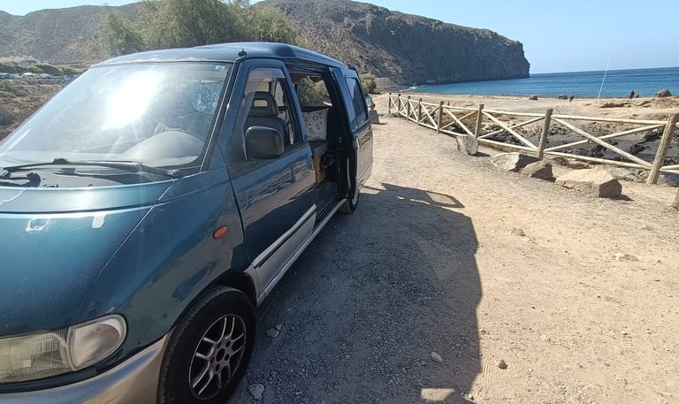 a van parked on a dirt road near a beach