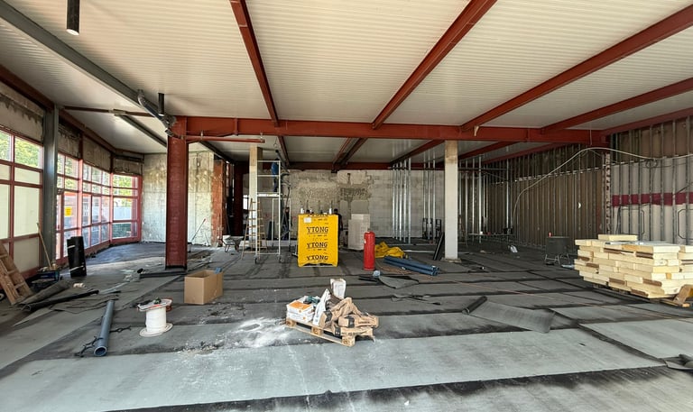Rohbau-Innenraum mit Stahlträgern, Dämmmaterial und Vorbereitungen für den Innenausbau
