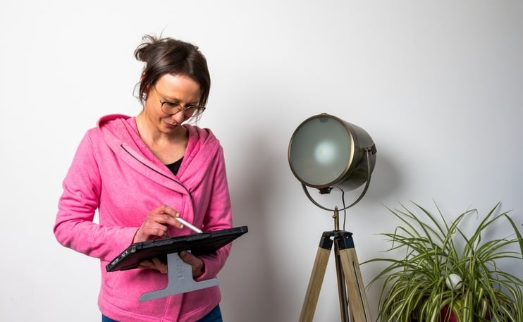 a woman in a pink jacket and jeans standing in front of a lamp