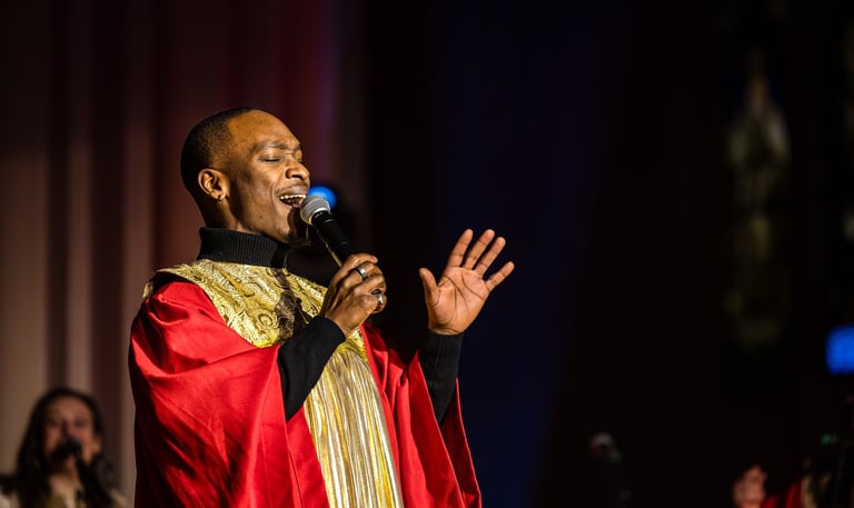 Un chanteur de gospel en toge dorée et rouge sur scène