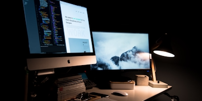 escritorio con 1 computadora con 2 monitores mostrando diseño de una web