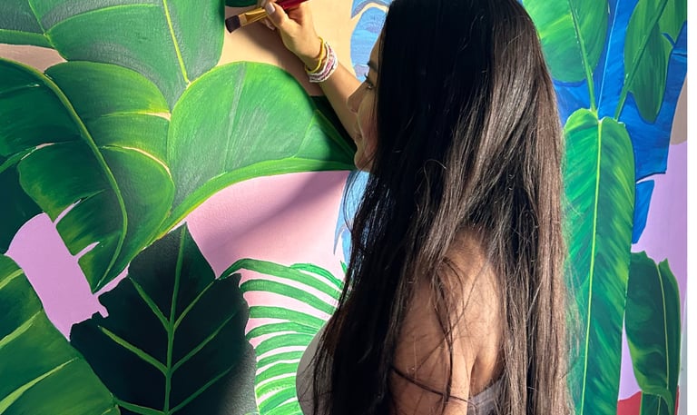 Pintora trabajando en mural artístico interior, arte contemporáneo personalizado con acrílico.