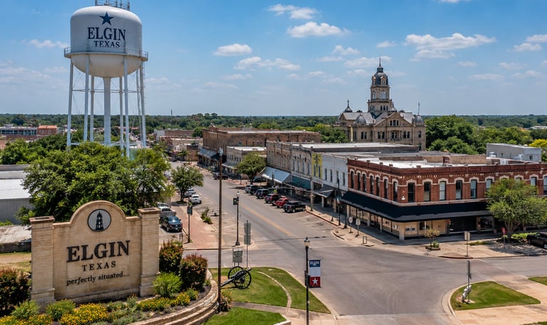 Elgin TX downtown skyline featuring the Elgin water tower, historic buildings, local streets